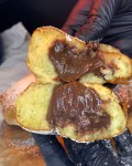 Two halves of a homemade donut filled with chocolate spread, dusted with powdered sugar